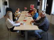 Spotkanie DKK Maj 2025 Grupa osób - członków Dyskusyjnego klubu książki w Urszulinie omawia przeczytane książki w tle plakat DKK.