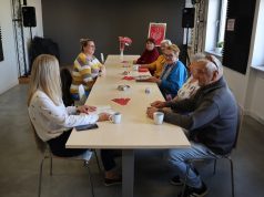 Spotkanie DKK Maj 2025 Grupa osób - członków Dyskusyjnego klubu książki w Urszulinie omawia przeczytane książki w tle plakat DKK.